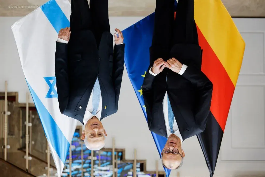 Two men in suits standing near Israeli and European Union flags Two men in suits standing near Israeli and European Union flags